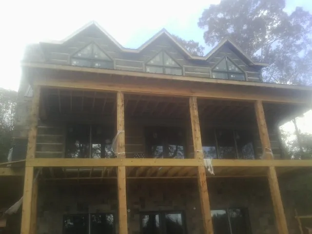 Dormers and porch framing on a large log home under construction — Roof Coating work by our crew in Milford Square