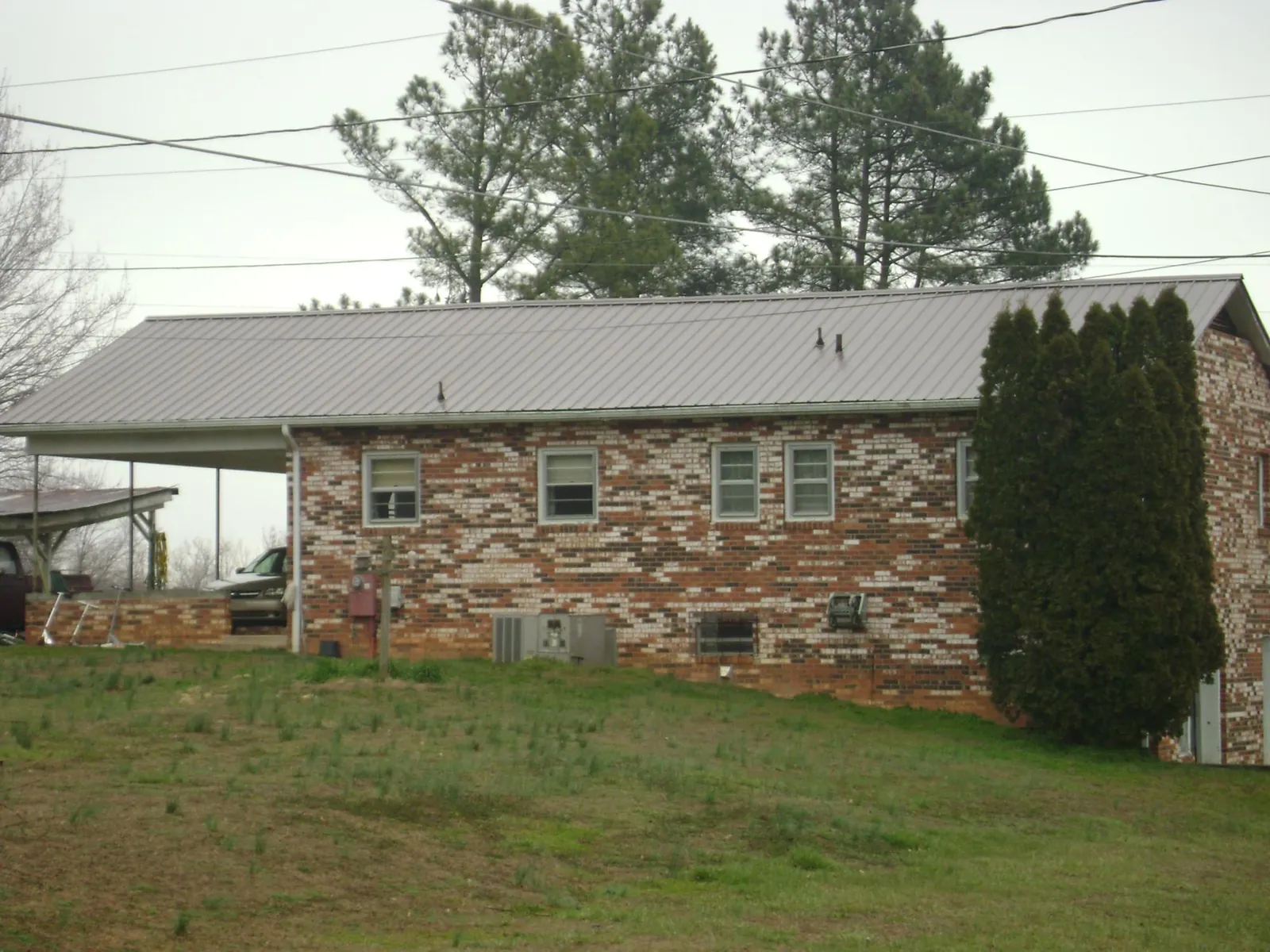 Gray metal roof on a brick split level home with a carport in Milford Square