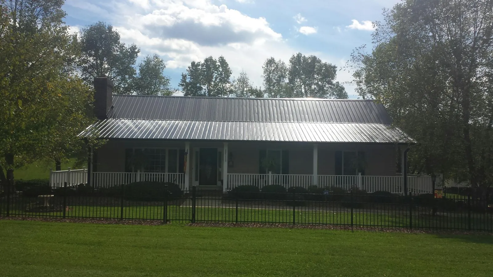 Gray metal roof on a brick ranch with a full width front porch — Gutter Guard Installation work by our crew in Milford Square