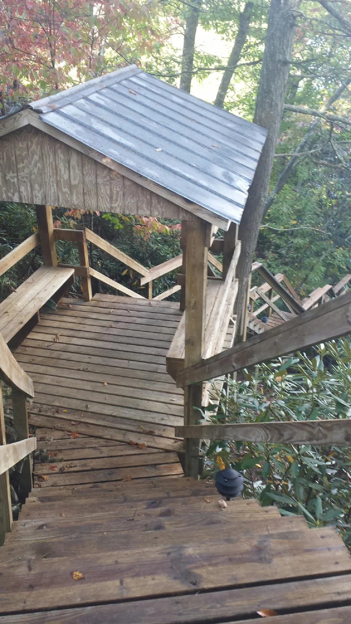 Metal roofed shelter over wooden steps on a wooded walkway — Skylight Repair & Installation work by our crew in Milford Square
