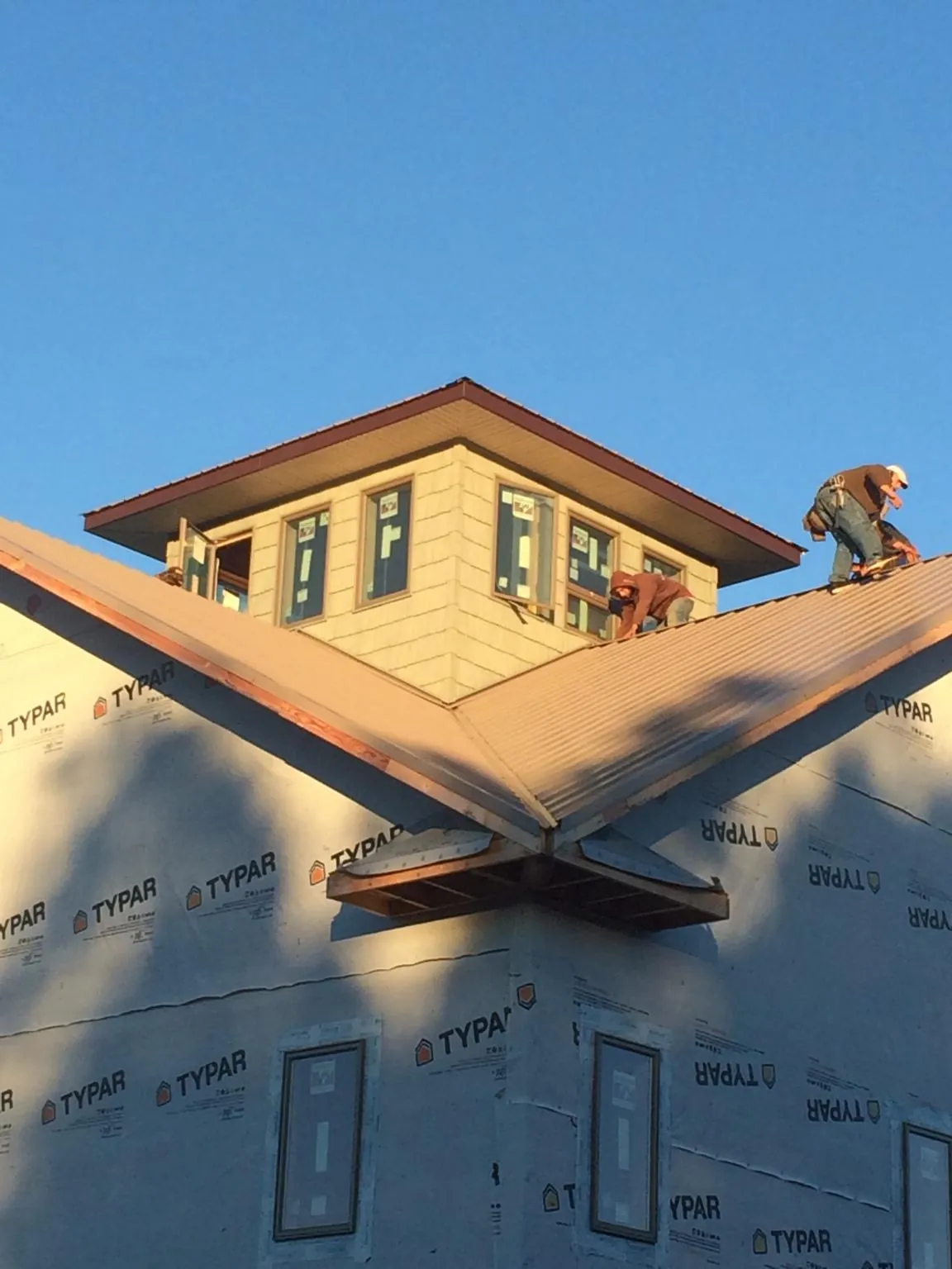 Roofers working around a rooftop cupola on a new metal roof at sunset — Roof Waterproofing in Milford Square by Roofing Brothers